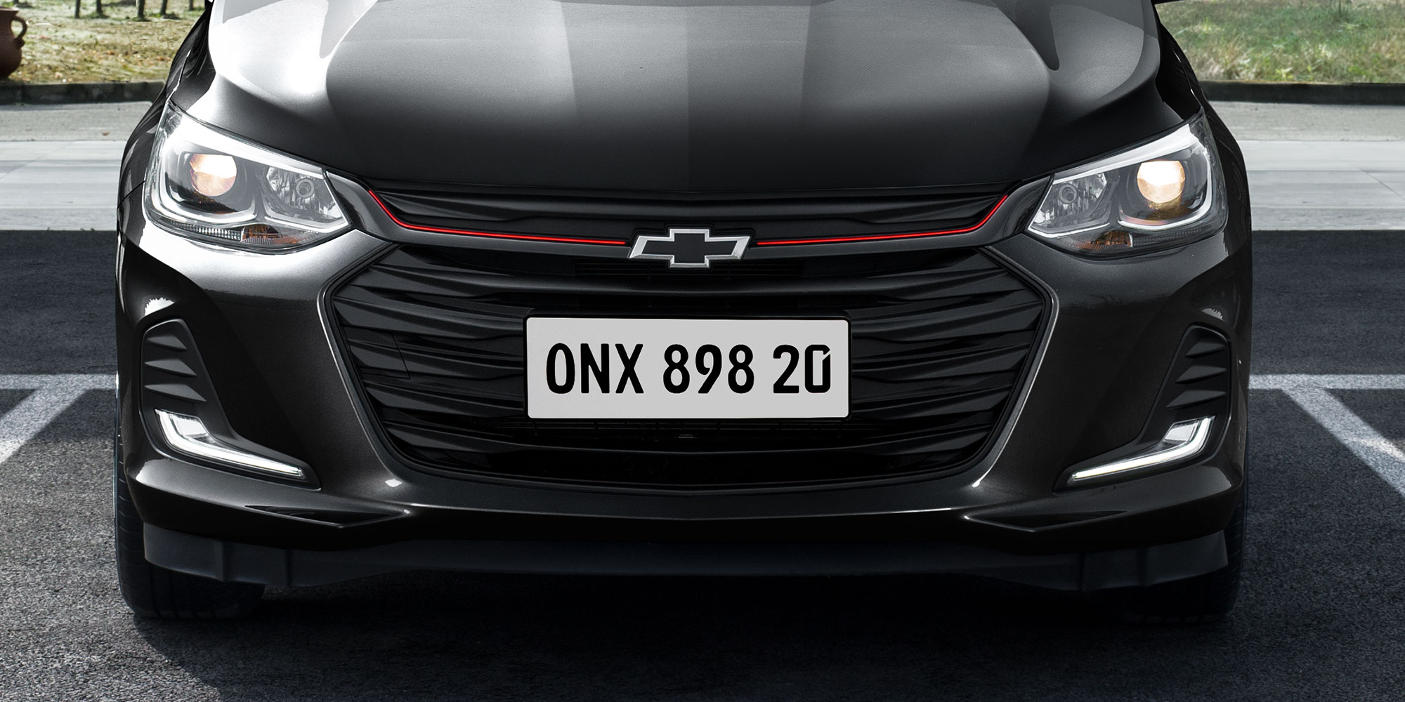 Chevrolet Onix 2025, sedán deportivo con detalles negros y acentos en rojo en parrilla frontal facsia, versión Redline
