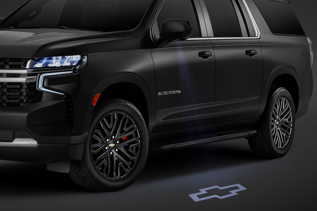 Suburban 2025, proyector de espejos con emblema Chevrolet reflejado en el piso y más accesorios eléctronicos